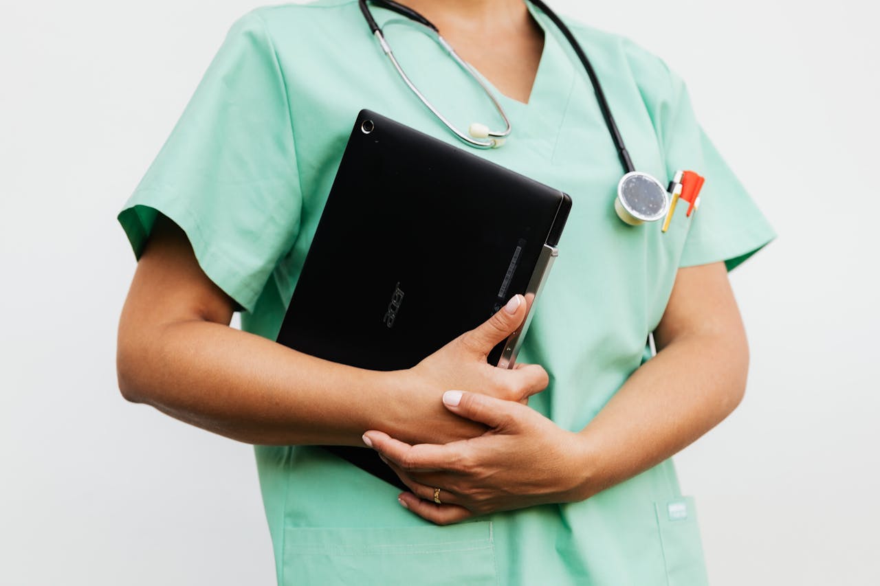 about-us Close-up of a nurse in green scrubs holding a tablet and stethoscope, symbolizing modern healthcare.